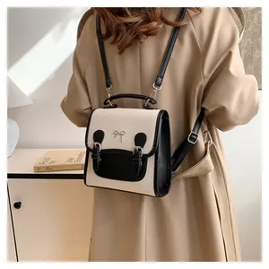 Detail of canvas mini backpack with black leather trim and metal bow decoration