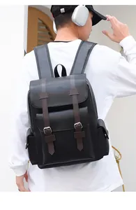 Outdoor back view of a black leather backpack with brown trim and silver buckle detailing