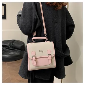 Close-up of color-block backpack with bow charm worn by a model in a grey coat