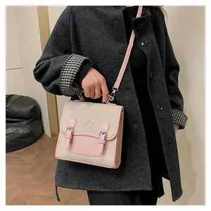 Detail of a mini beige two-tone backpack with pink straps and silver bow accent