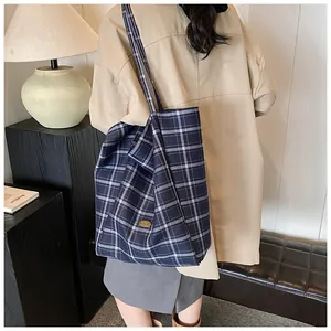 Detail of navy blue plaid canvas tote bag with golden handmade metal logo tag