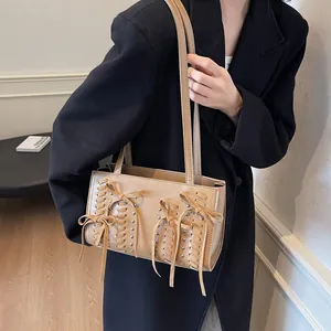 Brown suede shoulder bag with rivets and decorative bow ties for a stylish casual look
