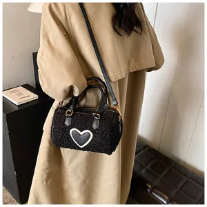 Cilindrische pluche tas met leren hart gedragen op een beige trenchcoat voor de herfstmode