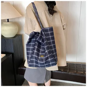 Detail view of large navy plaid canvas tote bag with metal logo and wide strap