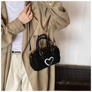 Detail van de zwarte pluche hart-handtas gecombineerd met een stijlvolle kaki trenchcoat