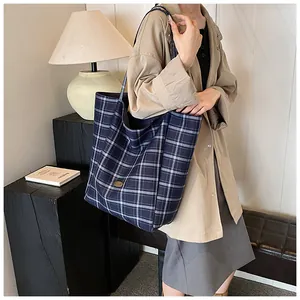 Detail of navy blue plaid canvas tote bag with golden logo and durable shoulder strap