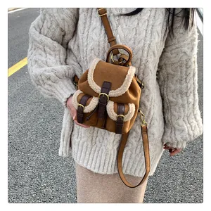 Close-up of caramel suede mini backpack featuring vintage gold buckles and cream faux fur trim