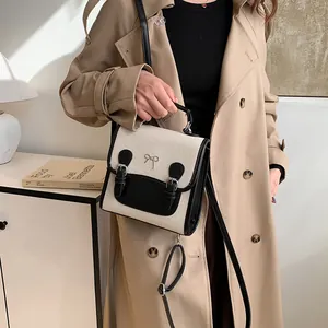 Chic beige canvas and black leather backpack with a decorative metal bow for women