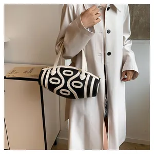 Close-up of contrast black and white cylindrical bucket bag with artistic curved lines