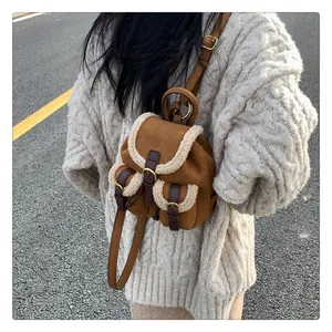 Detail of a brown suede mini backpack with white faux fur trim and retro buckle pockets