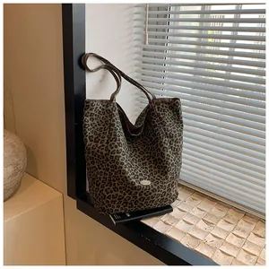 Close-up of leopard print tote bag with brown straps and handmade oval label on soft fabric