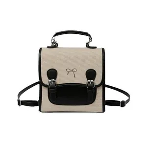 Preppy style beige canvas and black leather backpack with silver bow hardware and dual straps