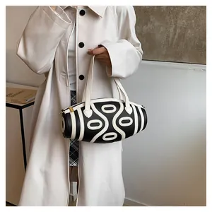 Detail of black cylinder handbag with white oval patterns and lychee leather texture