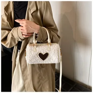Detail van witte pluizige handtas met bruin lederen hart en beige handvatten