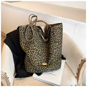 Close-up of leopard print tote bag with handmade metal logo and sturdy handles