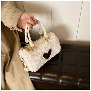 Detail van witte pluizige pluche tas met bruine hartvormige patch en gouden hardware