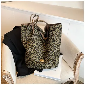 Detail of a vintage leopard print tote bag with a golden handmade logo on a white armchair
