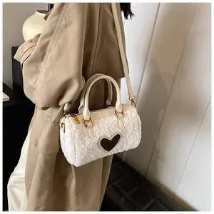 Detail van witte pluche cilindertas met bruin hartje en leren riem gedragen door een model