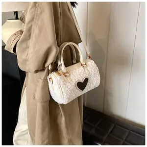 Detail van witte pluche Boston-tas met bruin lederen hartpatch en gouden hardware