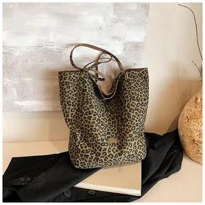 Close-up of leopard print tote bag with gold metal plate and wide canvas shoulder straps