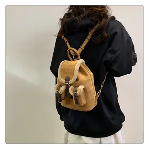 Close-up of brown suede mini backpack with white fleece trim and gold metal buckles
