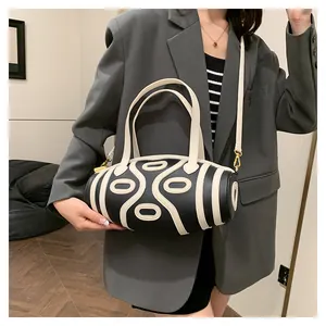 Detail of a black pebbled leather cylinder bag with white stripes and detachable strap