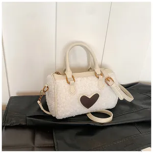 Detail van witte faux lamswollen tas met een bruine hartvormige lederen patch