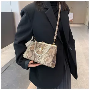 Détail du sac à main motif serpent avec poignée en perles et fermoir métallique doré