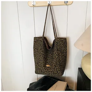 Detailed view of leopard print tote bag with golden metal logo plaque and slim shoulder strap