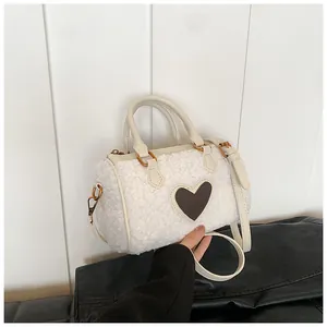 Detail van witte fleece handtas met bruin lederen hart en gouden metalen accessoires