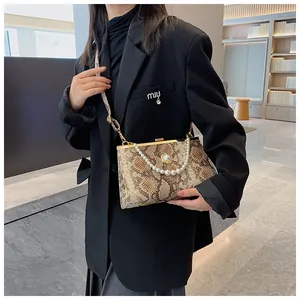 Détail du sac à main serpent avec boucle en perle et cadre métallique sur un blazer