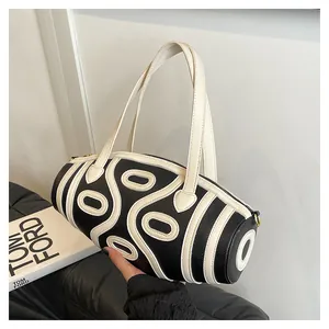 Detail of a cylinder bucket bag with black and white wavy leather stitching and dual handles