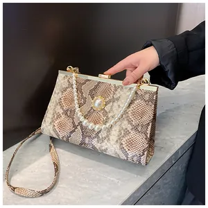 Détail du sac à main texture serpent avec poignée en perles et fermoir doré chic