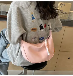 Detailansicht der rosa Halbmond-Schultertasche mit dekorativem weißem Seilknoten-Anhänger