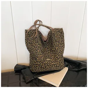 Detailed macro view of leopard print tote bag with brown handles and handmade metal tag