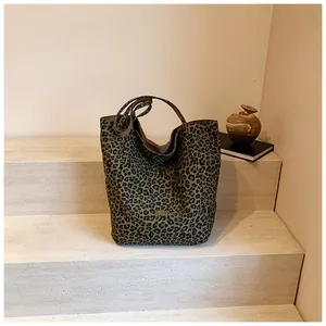 Detail of leopard print tote bag with metal logo on stone steps with decorative props