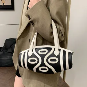 Chic black and white striped bucket bag with sleek round design shown on shoulder