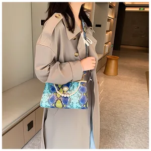 Détail du sac à main en serpent bleu et jaune avec poignée en perles et fermoir métallique