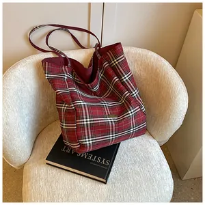 Detailed macro view of classic red and black tartan canvas tote bag with golden metal logo
