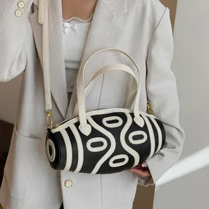 Minimalist black and white cylinder bucket bag with geometric stripes and golden hardware