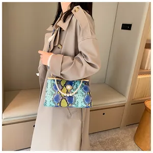 Détail du sac à main texturé peau de serpent avec poignée en perles et fermoir métallique