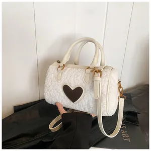 Detail van witte pluche cilindertas met bruine hartpatch en leren handgrepen