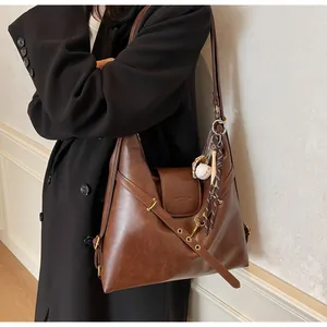 Detalle de bolso tote de cuero marrón oscuro con texto grabado y hebilla metálica