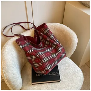 Detailed close-up of a red and black plaid tote bag resting on a white textured chair