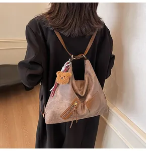 Detail of vintage brown tote bag featuring side zipper pocket and plush bear pendant accessory