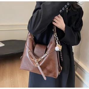 Detalle del bolso tote de cuero marrón vintage con correas de ojales metálicos y logo grabado