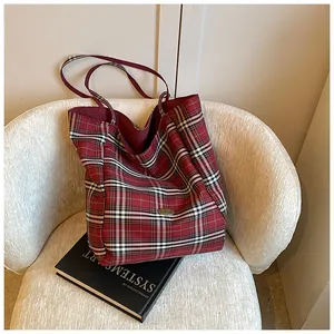 Close-up of red plaid canvas tote bag with metal logo on a cozy sheepskin texture