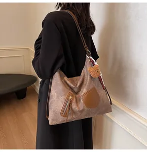 Detailed close-up of a vintage brown tote bag with plush bear charm and silk scarf accent