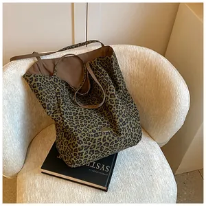 Detail of leopard print tote bag with metal nameplate on a white fabric armchair