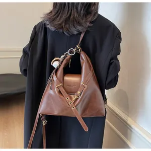 Detalle de bolso hobo de cuero marrón vintage con hebilla de metal y letras de moda